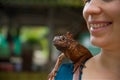 Huge brown iguana sits on the womanÃ¢â¬â¢s shoulder
